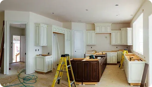 A partially finished kitchen with white cabinets and a dark wooden island