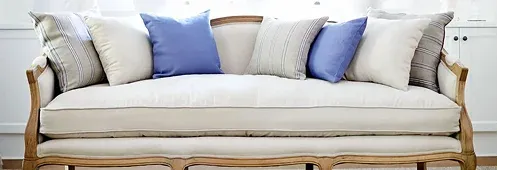 A stylish, light-colored sofa with a wooden frame