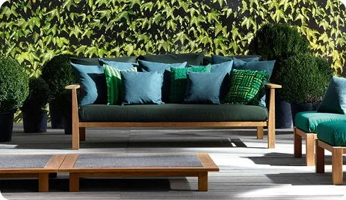A stylish outdoor seating area featuring a wooden sofa with green cushions