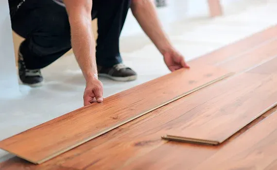 Person installing wooden floor planks indoors